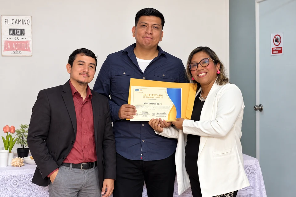 Integrante de KJA con camisa azul oscuro y su reconocimiento junto al equipo